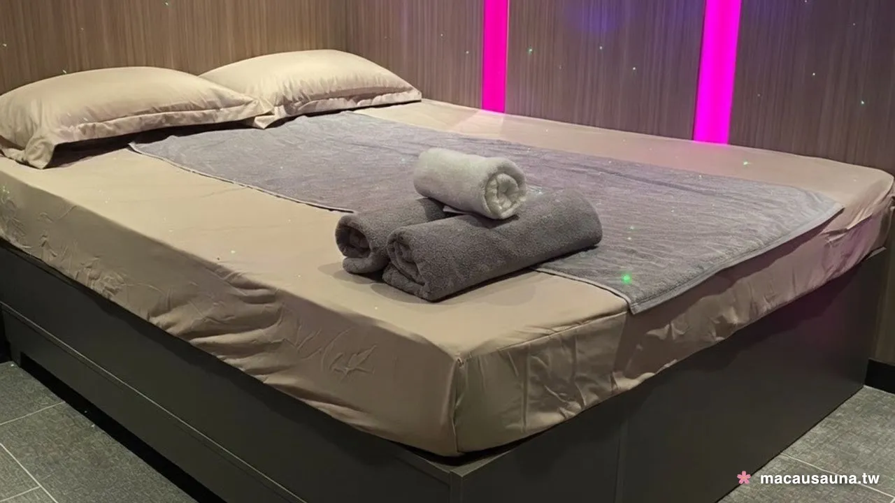澳門桑拿尚品國際水療的星空主題睡房，木紋牆面點著星點，兩道粉紫燈帶貼在牆縫裡，床上放著捲好的毛巾